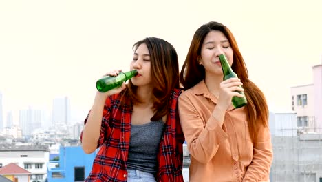 Junge-asiatische-Frau-lesbisches-Paar-klirrende-Flaschen-Bier-party-am-Dach.