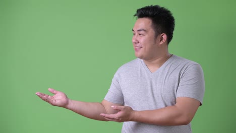 Young-handsome-overweight-Asian-man-against-green-background