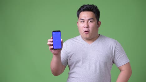 Young-handsome-overweight-Asian-man-against-green-background