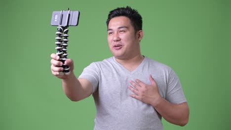 Young-handsome-overweight-Asian-man-against-green-background