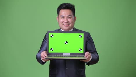 Young-handsome-overweight-Asian-businessman-against-green-background