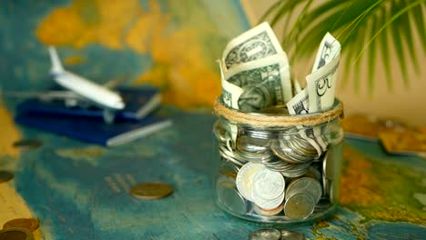 Travel-budget-concept.-Money-saved-for-vacation-in-glass-jar-on-world-map-background