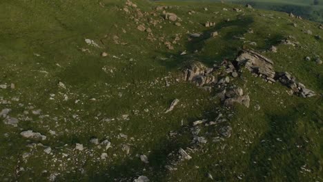 A-view-from-above-on-a-valley-strewn-with-huge-stones-at-the-foot-of-a-high-cliff.-A-sunset-panorama-of-the-Caucasus-with-a-turn.-Review-of-the-epic-place-in-4k-100mbps