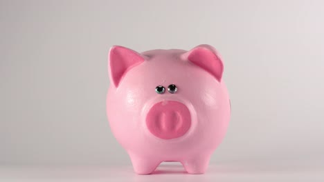 TIME-LAPSE:-Male-hand-throws-coins-into-a-pink-piggy-moneybox