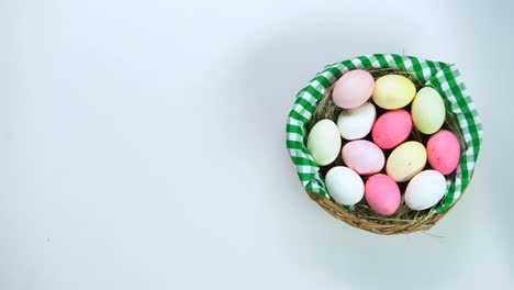 Woman-hand-putting-happy-Easter-decoration-near-basket-painted-eggs,-holiday