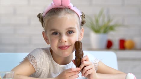 Adorable-chica-jugando-con-conejito-de-chocolate-y-sonriendo-a-cámara,-infancia