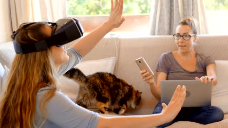 Lesbian-couple-using-virtual-reality-headset-and-laptop-in-living-room-4k