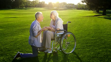 Husband-tenderly-kissing-wife-hands-on-wheelchair