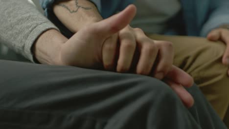 Close-Up-of-Two-Male-Hands-Gently-Touching-and-Holding-Each-Other.-Cute-Queer-Relationship-Concept.-Gay-Couple-are-Casually-Dressed.-Room-is-Bright-and-Sunny.