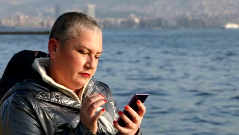 Mujer-con-smartphone-cerca-del-mar