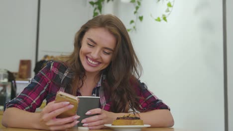 Smiling-Woman-Using-Mobile-Phone-And-Drinking-Coffee-Indoors