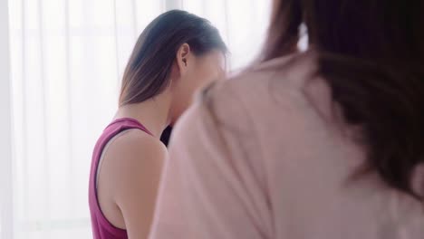 Young-Asian-women-lesbian-happy-couple-using-smartphone-checking-social-media-in-bedroom-at-home,-enjoy-love-moment-while-near-the-window-when-relaxed.-Lifestyle-LGBT-couple-together-indoors-concept.