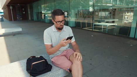 Kerl-mit-Smartphone-draußen-sitzen.