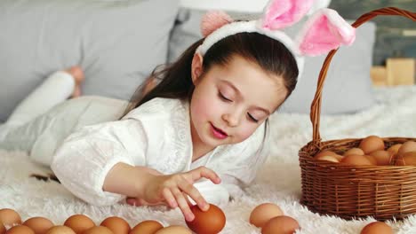 Chica-feliz-jugando-con-huevos-de-Pascua-en-la-cama