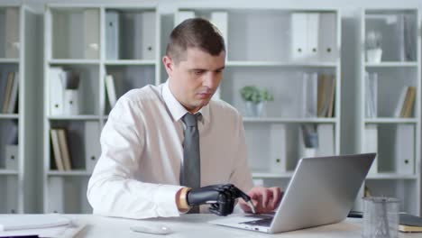 Hombre-de-negocios-con-brazo-protésico-mecanografía-en-Laptop