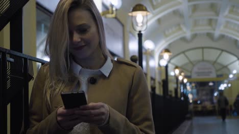 Una-joven-hermosa-mujer-trabaja-en-un-teléfono-inteligente-en-un-pasillo