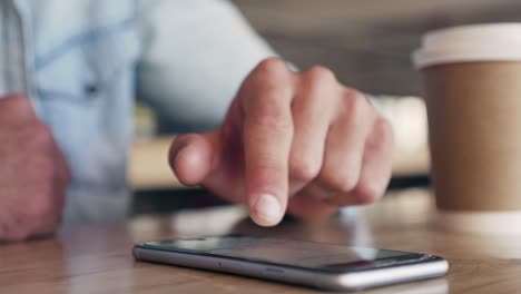 male-hand-typing-Messaging-on-Mobile-Phone-On-Table