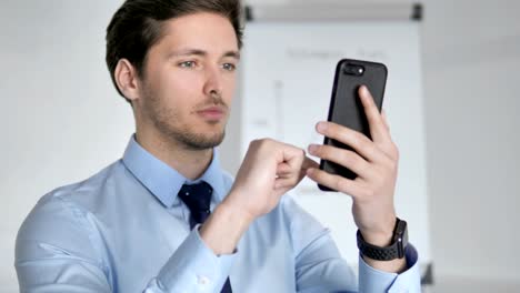 Close-Up-of-Young-Businessman-Using-Smartphone-at-Work