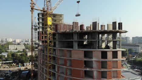 An-aerial-view-of-a-residential-building-in-construction.-Tower-cranes-working-by-the-building.-4K