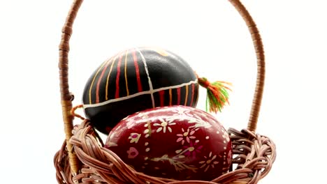 decorative-basket-with-painted-Easter-eggs-on-white-background