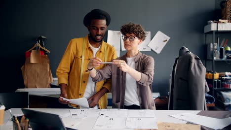 Couple-of-designers-shooting-flat-lay-taking-photo-of-sketches-on-sewing-table