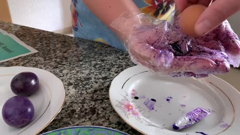 A-woman-in-gloves-paints-eggs