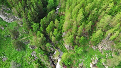 Drone-flying-over-a-green-forest-with-waterfall-in-the-Altai-mountains