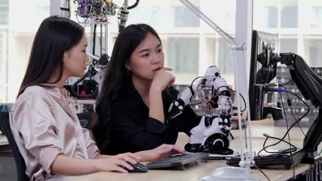 Asian-young-electronics-engineer-try-to-fix-robot-at-lab.-Technology-and-innovation-concept.