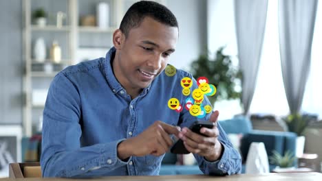 Happy-African-Man-Using-Smartphone,-Emojis,-Smileys-and-Likes