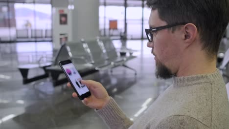 El-hombre-está-viendo-el-catálogo-de-la-tienda-de-ropa-en-línea-en-el-teléfono-inteligente