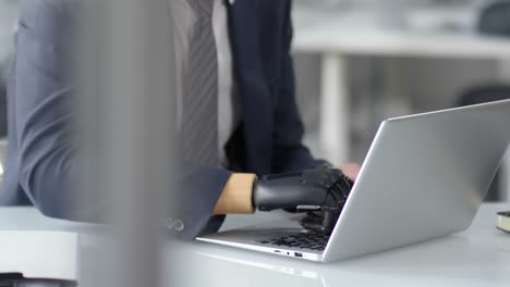 Businessman-with-Prosthetic-Hand-Working-on-Laptop-in-Office