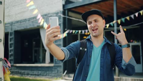 Cámara-lenta-de-hombre-alegre-tomando-selfie-al-aire-libre-usando-la-cámara-del-teléfono-inteligente