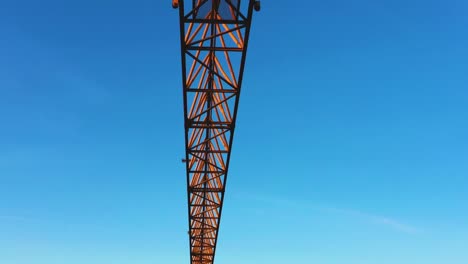 A-construction-crane-swaying-slightly-in-the-wind-against-the-morning-sky.-Close-up,-aerial-video