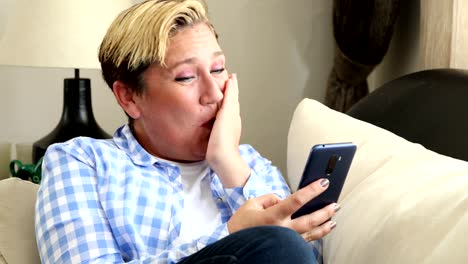 Woman-with-smart-phone-laughing-at-the-home