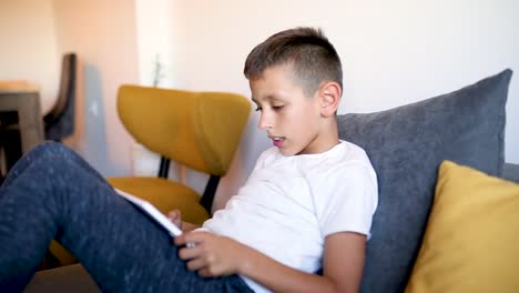 Young-boy-is-playing-games-on-his-tablet-at-home