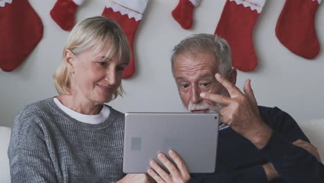 senior-elderly-Caucasian-old-man-and-woman-using-tablet-and-playing-internet-online-together