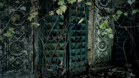 Abandoned-ancient-building-with-ornamental-gateway-decoration-in-woods-leaves