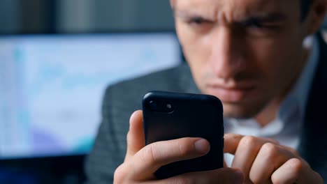 Close-up-of-a-successful-businessman-in-a-suit-is-using-a-smartphone-in-the-office-at-the-workplace.-Man-uses-the-application-on-a-mobile-phone,-office-on-the-background