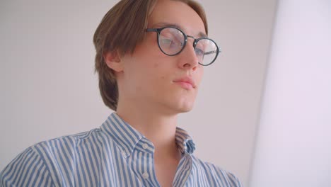 Closeup-portrait-of-young-attractive-caucasian-businessman-working-on-the-laptop-looking-at-camera-sitting-in-the-armchair-indoors