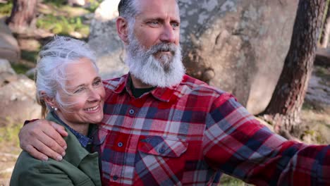 De-cerca-pareja-mayor-tomando-selfie-con-teléfono-inteligente-en-el-bosque