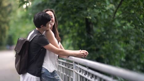 Two-young-girls-hugs,-kisses-and-talk-on-a-bridge