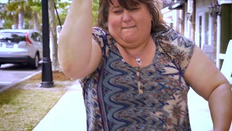 Una-mujer-con-sobrepeso-feliz-bailando-en-una-acera-en-un-barrio-comercial-de-la-ciudad