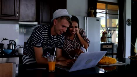 Couple-Use-Laptop-Computer-Embracing,-Happy-Young-Woman-And-Man-In-Kitchen-Studio-Talking-Modern-House-Interior