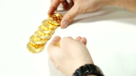 Men's-hands-spread-the-gold-coins-bitcoin-on-the-table.-Cryptocurrency-in-the-form-of-gold.