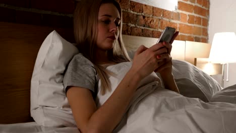 Mujer-en-la-cama-viendo,-desplazamiento-en-Smartphone-en-la-noche