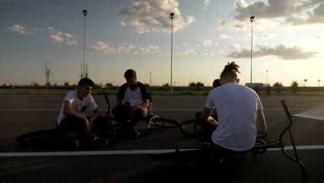 Young-bikers-friends-relaxing-after-training-lying-down-and-using-their-smartphones-addicted-to-smart-technology