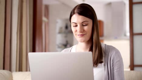 Atractiva-mujer-de-sonrisa-profesional-trabajando-en-ordenador-portátil-en-casa.-Concepto-de-la-oficina-en-casa