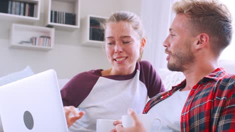 Joven-pareja-hablar,-utilizando-la-computadora-portátil-en-casa,-cerrar-vista-de-lado