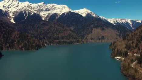 Aero-disparos-de-nieve-nevadas-grandes-montañas-y-lago-azul-en-día-de-verano