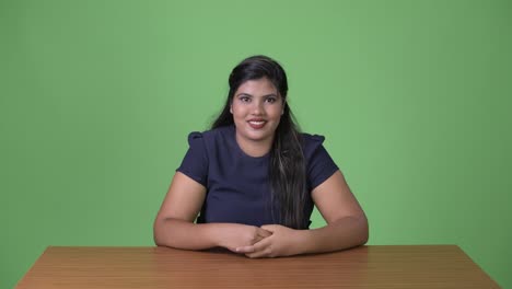 Young-overweight-beautiful-Indian-businesswoman-against-green-background